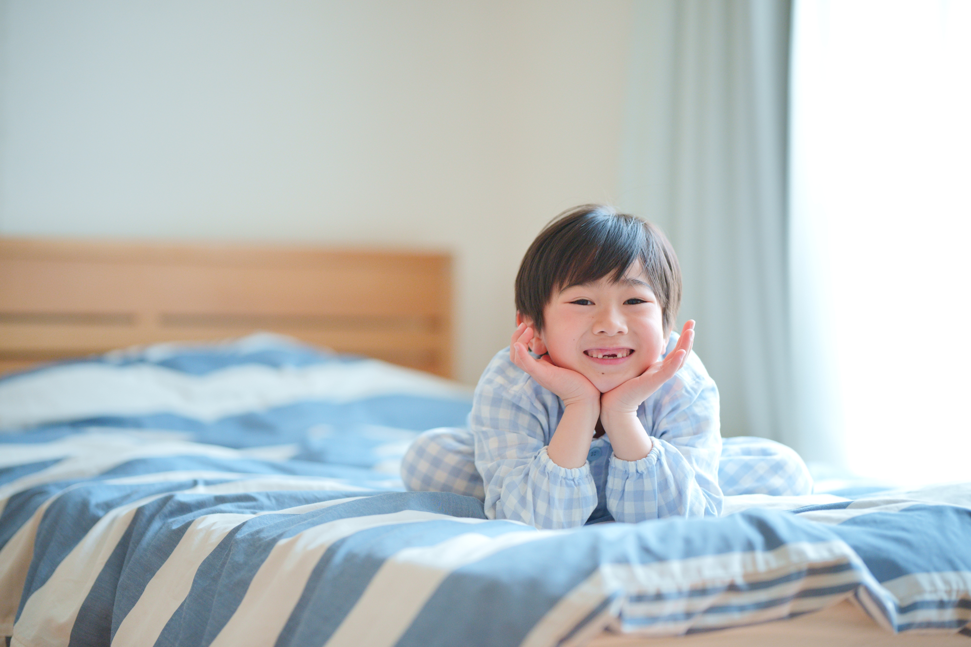 ベッドで頬杖を突く子ども
