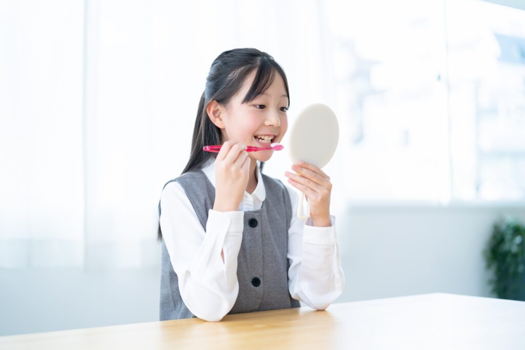 鏡を持ち歯磨きを持つ若い女の子