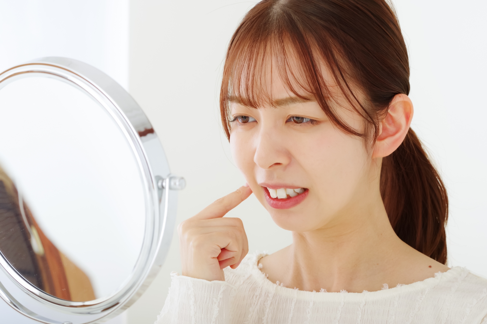 口のトラブルを気にする若い女性