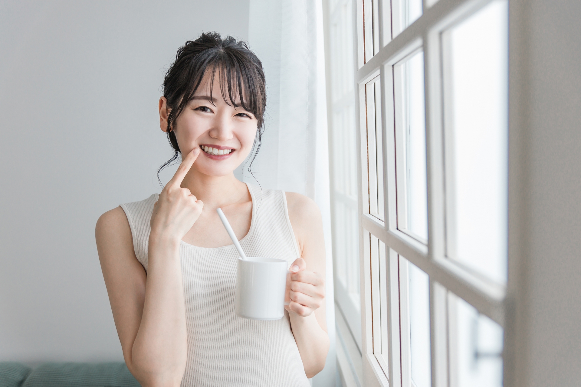 口元を指さす女性
