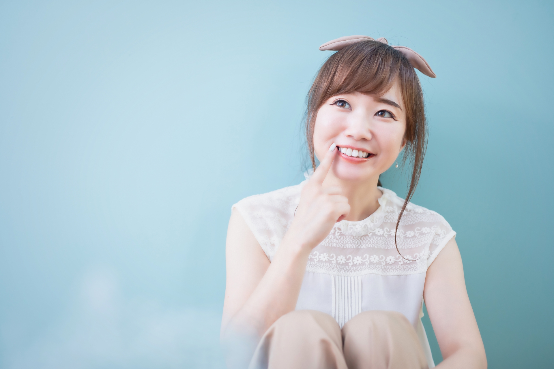 口元を指さす女性